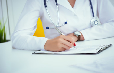 Close-up view of female doctor hands filling patient registration form. Healthcare and medical...