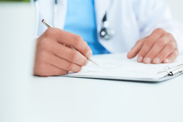 Closeup of male doctor's hands taking notes or fills in the client's medical card or prescribes medication. Ward round, patient visit check, medical calculation and statistics concept.