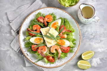 Healthy lettuce salad with arugula, large shrimps, cherry tomatoes, boiled egg, brie cheese and grated parmesan cheese.