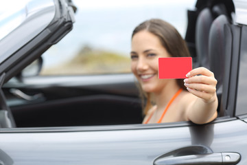 Driver showing a blank credit card in a car on vacation