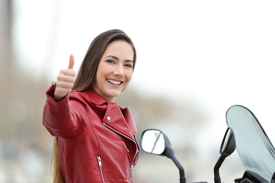Motorcyclist looking at camera with thumb up outdoors