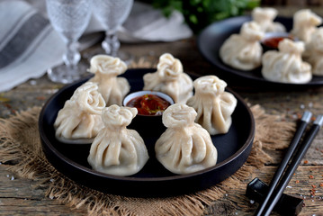 Georgian homemade khinkali (dumplings) with meat and red sauce on an old wooden background. Rustic style.