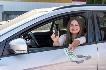 Woman showing dollars and key from car window