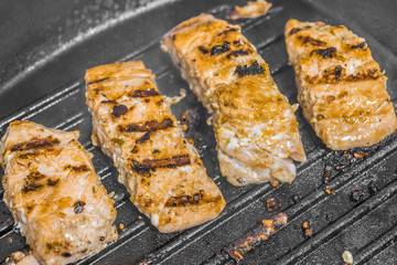Slices of roasted salmon in a grill pan