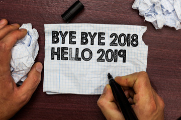 Conceptual hand writing showing Bye Bye 2018 Hello 2019. Business photo text Starting new year Motivational message 2018 is over Hand hold pen sketch word on torn page woody deck hand paper ball. © A