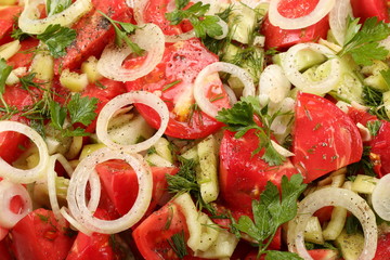 Sliced tomatoes, cucumbers, parsley leaves and dill, spices and olive oil. Fresh vegetable salad close-up