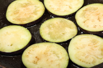 Sliced eggplants fry in a pot with oil