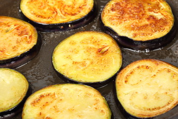 Sliced eggplants fry in a pot with oil