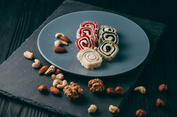 Traditional oriental sweets and nuts: hazelnuts, cashews on a dark wooden background. Turkish dessert is the Rakhat locus. View from above. Place under the text.