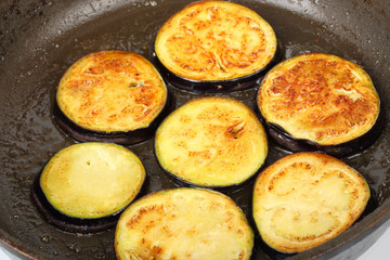 Sliced eggplants fry in a pot with oil