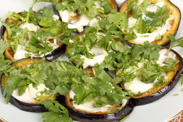 Sliced roasted eggplants with mayonnaise and cilantro in a porcelain plate