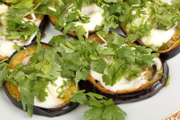 Sliced roasted eggplants with mayonnaise and cilantro in a porcelain plate