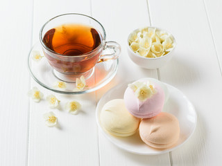Herbal tea, a bowl of marshmallows and jasmine flowers on a table. The composition of the morning Breakfast.