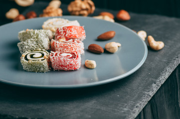 Traditional oriental sweets and nuts: hazelnuts, cashews on a dark wooden background. Turkish dessert is the Rakhat locus. View from above. Place under the text.