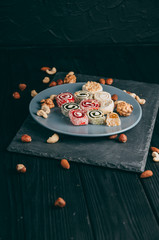 Traditional oriental sweets and nuts: hazelnuts, cashews on a dark wooden background. Turkish dessert is the Rakhat locus. View from above. Place under the text.