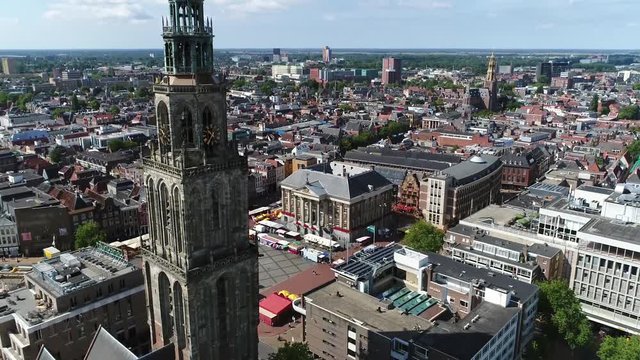 Aerial footage of the Martinitoren also called the St. Martin's Tower is highest church steeple in city of Groningen Netherlands and the bell tower of the Martinikerk als showing Grote Markt 4k