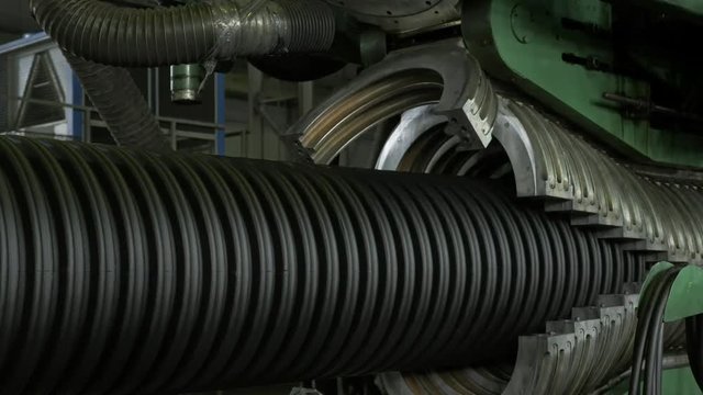 Manufacture of plastic water pipes. Manufacturing of tubes to the factory. The process of making plastic pipes on the machine tool with the use of water and air pressure. Special corrugated forms of
