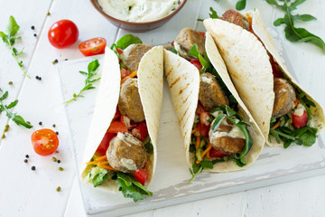 Arabic cuisine. Concept of vegetarian food. Delicious fresh homemade vegetarian tortilla with falafel on a wooden kitchen table. Street food, fast food.