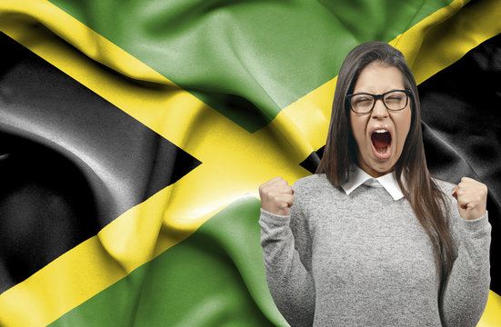 Ecstatic woman holidng fists and screaming against flag of Jamaica