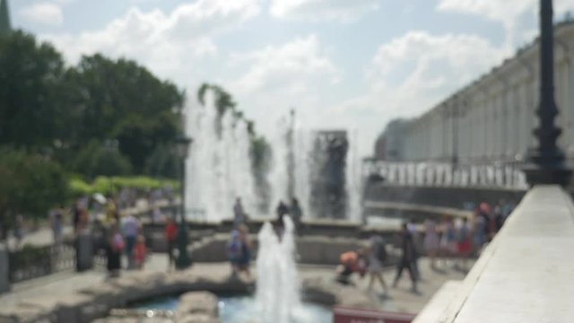 City park with fountains. People relax and walk with children. In summer time. Not in focus is intentional.
