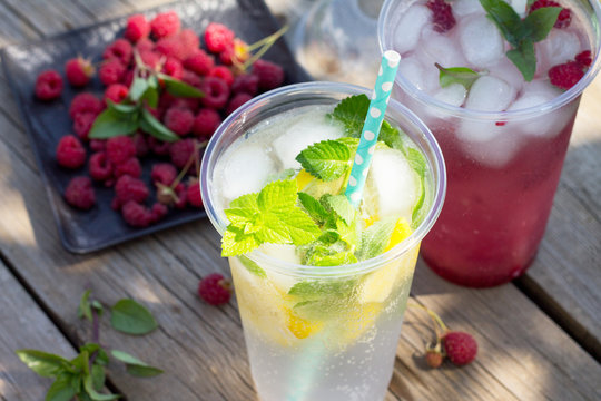 SOFT DRINKS. Refreshing summer drink lemon with mint, ice and raspberry with basil, ice. Glasses with cold and healthy beverage in a rustic style.