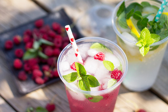 SOFT DRINKS. Refreshing summer drink lemon with mint, ice and raspberry with basil, ice. Glasses with cold and healthy beverage in a rustic style.