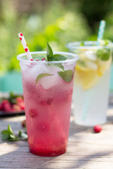 SOFT DRINKS. Refreshing summer drink lemon with mint, ice and raspberry with basil, ice. Glasses with cold and healthy beverage in a rustic style.