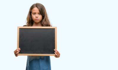 Brunette hispanic girl holding blackboard with a confident expression on smart face thinking serious