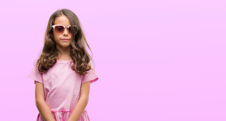 Brunette hispanic girl wearing sunglasses with a confident expression on smart face thinking serious