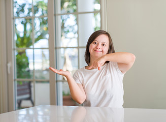 Down syndrome woman at home very happy pointing with hand and finger