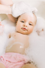 Happy little baby a swimming in the bathroom.Portrait of baby bathing in a bath with foam
