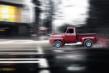 alter amerikanischer roter Oldtimer fährt schnell auf einer nassen Straße in der Stadt