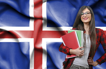 Happy female student holdimg books against national flag of Iceland