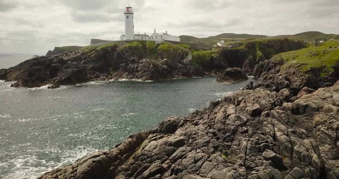 Fanal Head lighthouse in Ireland. Drone footage, flying over the coastal rocks and sea, revealing the attractive building.