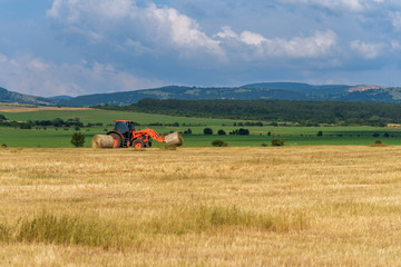 Fototapeta premium Tractor lifting hay bale on barrow.