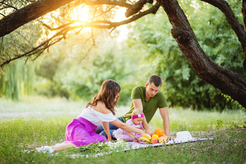 Cheerful family sitting on the grass during a picnic in a park