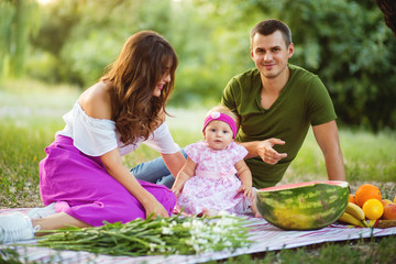 Beautiful family enjoying picnic time on the sunset.