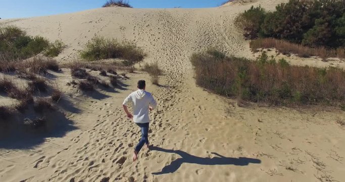 Aerial shot following person running up and over sand dunes Nags Head, North Carolina.