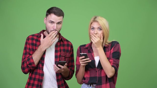 Young couple using phone and looking shocked together