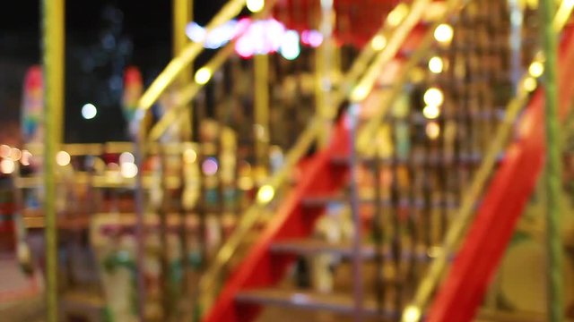 Bright carousel with shiny lights turning around in darkness of night outdoor. Real time full hd video footage.
