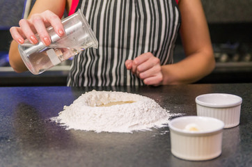 Woman preparing pizza dough on black granite table