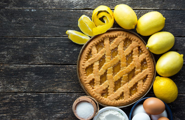 Delicious lemon pie with cooking ingredients on the wooden table 