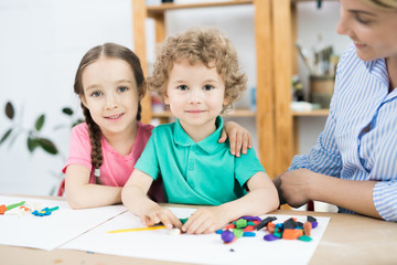 Fototapeta premium Portrait of little boy and girl embracing at the table while sitting in art and craft lesson