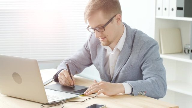 Office work concept. A young male designer works on a graphic tablet