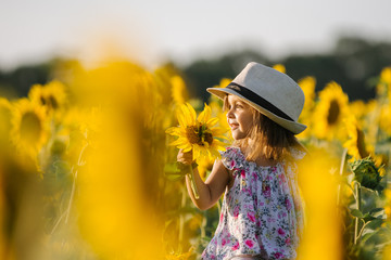 Fototapeta premium Happy little girl on the field of sunflowers in summer. beautiful little girl in sunflowers