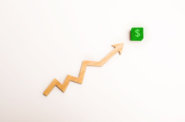 Wooden arrow up arrow points to a green block with a dollar symbol. The concept of revenue growth...