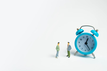 Two men stand near the blue alarm clock and talk. The concept of waiting for a meeting, a date. Punctuality. The cost of hourly work of a specialist, business planning. Discussing cases.