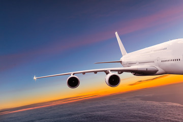 Naklejka na ściany i meble Big commercial airplane flying above dramatic clouds.