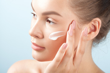 Young beautiful woman applies cream on clean perfect skin