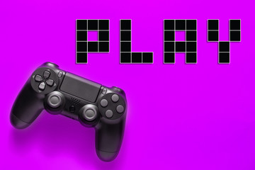 Black modern gamepad and word play on a colored background . Gaming concept